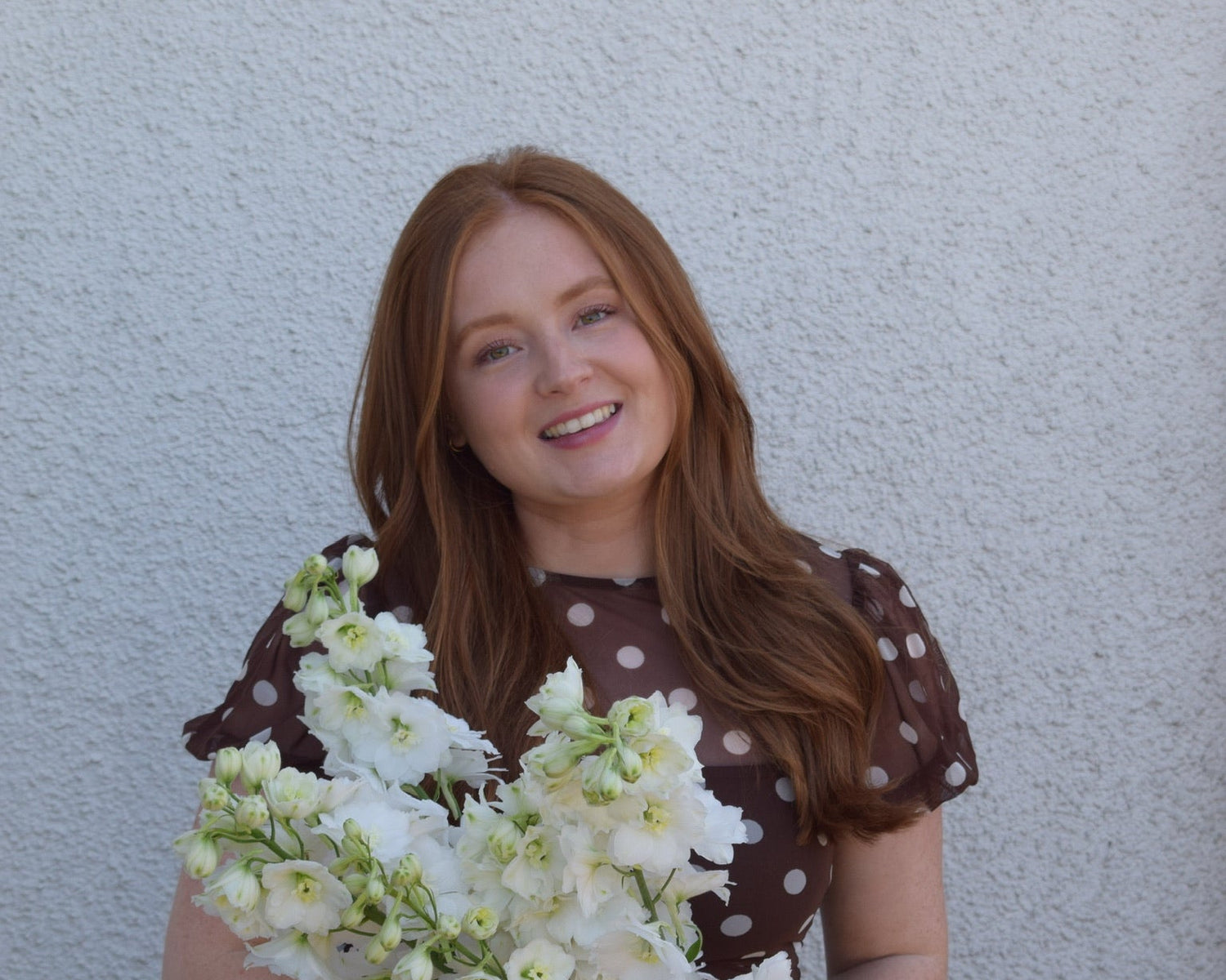 Woman holding a bouquet of flowers against a plain background