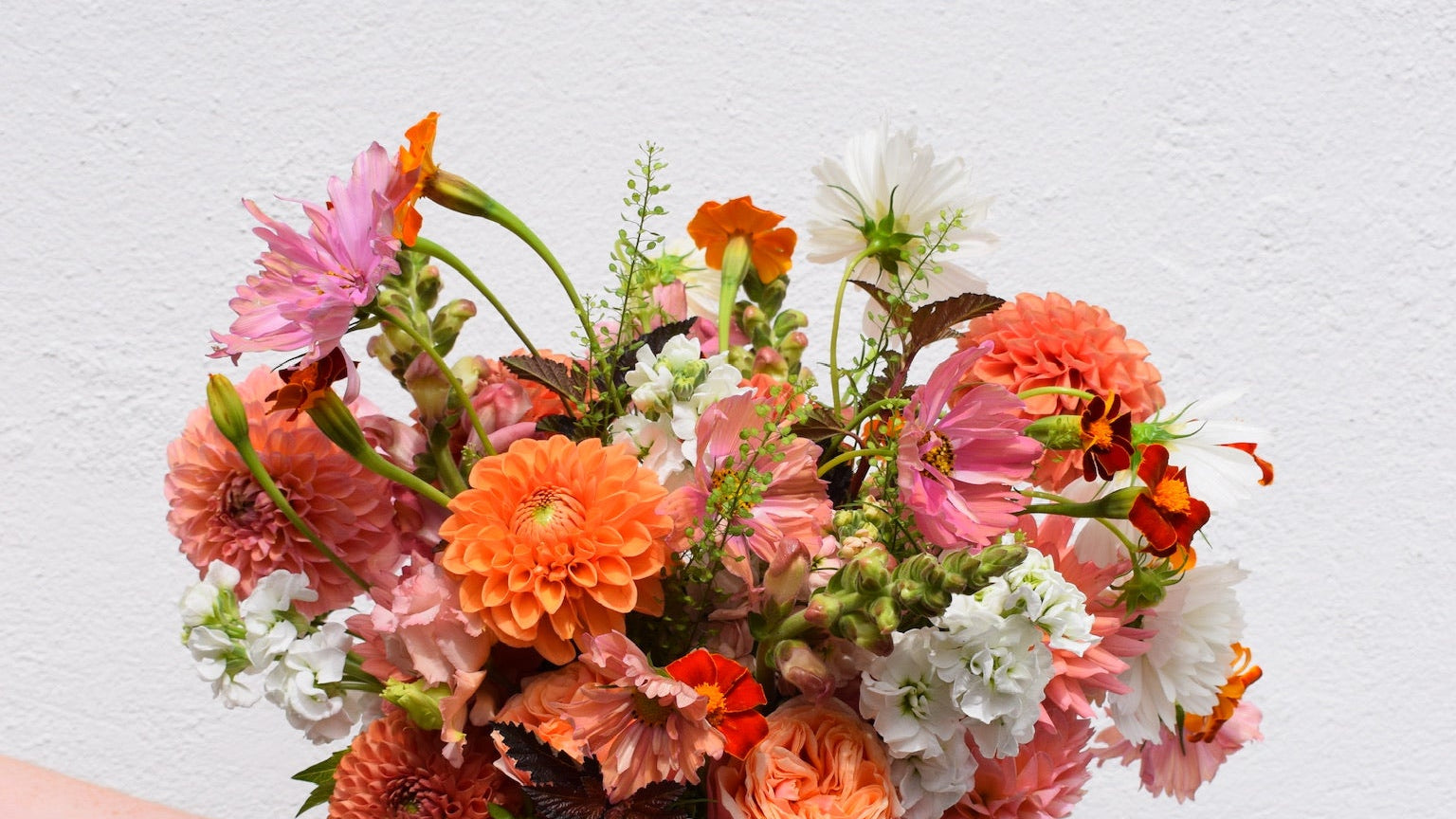 Bouquet of flowers held by a hand on a light gray background
